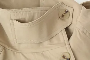 Gedetailleerd overzicht van de schouderband en getextureerde knopen op een kaki trenchcoat