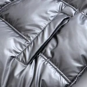 Detailed macro view of metallic silver shiny puffer jacket fabric and zippered pocket