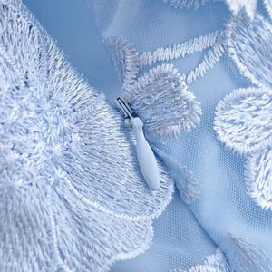 Detailed view of invisible zipper and 3D floral lace embroidery on blue dress.