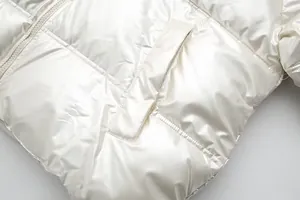 Close-up detail of a white metallic finish puffer jacket with quilted pocket texture