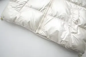 Detailed view of a metallic glossy white padded jacket featuring a zipper and drawstring hem.