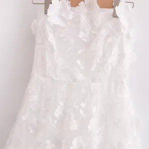 Close-up of white strapless dress with intricate 3D floral embroidery and lace details.