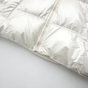 Close-up detail of the metallic shiny white puffer jacket showing zipper and quilted pattern