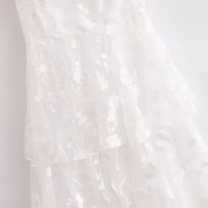Macro view showing the delicate white floral embroidery on a tiered luxury dress