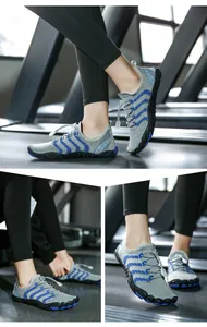 Dettaglio scarpe da scoglio grigie e blu traspiranti su tapis roulant in palestra