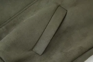 Detailopname van de olijfgroene suèdestof en paspelzak van het retro damesjack