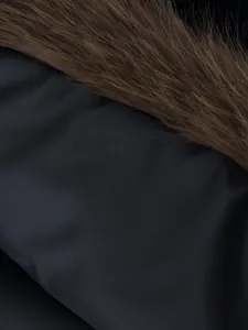 Macro detail shot of a black vest showing soft brown faux fur trim and fabric