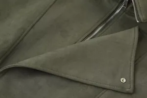 Detailopname van olijfgroene imitatiesuède jas met rits en stikseldetails aan kraag.
