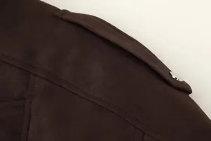Gedetailleerde weergave van de epaulet en zilveren knoop op een bruin suède jack