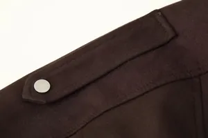 Macrodetail van een donkerbruin suède jasje met schouderpas en drukknoopsluiting