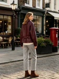 Back view of a stylish burgundy faux leather jacket with belt in a street setting