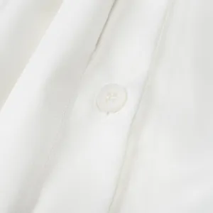 Detailed close-up of a white satin blouse showing smooth fabric texture and pearl button