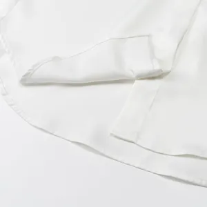 Macro view showing the curved hem and fine stitching of a white silk satin shirt