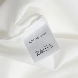 Macro detail showing the 100% polyester care and wash label on a white satin blouse