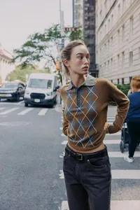 Détail d'un pull polo en maille à losanges marron pour femme en décor urbain