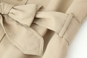 Macrodetail van een kaki trenchcoat met de tailleriem en de textuur van de stof