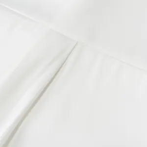 Macro view showing the smooth texture and fine stitching of a white silk satin shirt