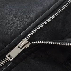 Close-up of high-quality silver metal zipper on a black vintage faux leather biker jacket.