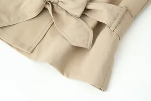 Detailopname van een kaki trenchcoat met een getailleerde riem en hoogwaardige stiksels