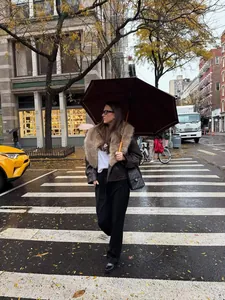 Femme portant une veste en similicuir marron avec col en fausse fourrure en ville.