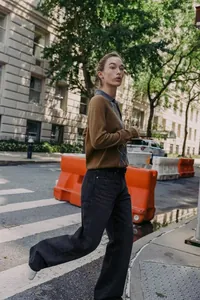 Polo en maille à losanges chic porté avec un jean large dans un décor de rue urbain.