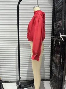 Side view detail of a red long-sleeve blouse with stand collar and bow on a mannequin