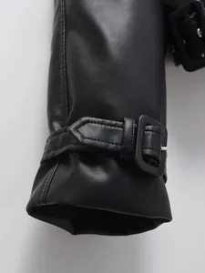 Detailed macro view of black faux leather jacket cuff with adjustable buckle strap