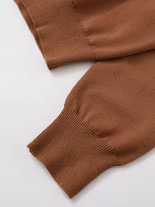 Gros plan des poignets côtelés d'un polo en maille marron montrant la texture du tissu