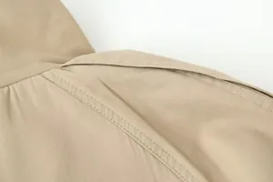 Detailopname van een kaki trenchcoat met hoogwaardige stiksels en textuur van de stof