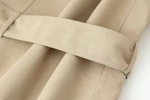 Detailopname van een riem van een kaki trenchcoat met fijne stiksels en twillstof