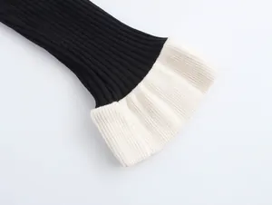 Detail of a black ribbed knit sweater with contrasting white layered cuffs