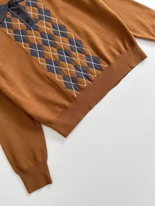 Détail d'un polo en maille marron pour femme avec un motif à losanges gris classique