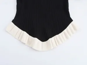 Close-up detail of the black ribbed knit fabric and contrast white ruffled hem design