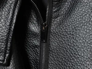 Makroaufnahme einer schwarzen Kunstlederjacke mit Narbenprägung und Metallreißverschluss