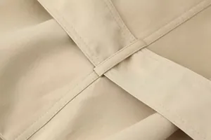 Detailopname van riemlus en stiksel van een klassieke kaki trenchcoat voor dames