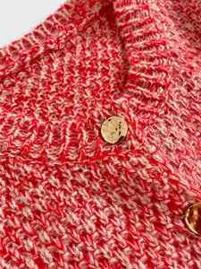 Detailed macro shot of red and white mixed knit fabric with gold metal buttons