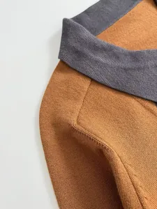 Gros plan du col gris et du tissu marron d'un polo en maille pour femme.