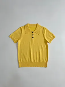 Detail view of yellow short-sleeve knit polo shirt with black buttons and collar.