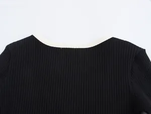 Detail of a black ribbed knit top featuring a white contrast neckline and soft texture.