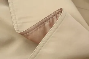 Detailopname van een kaki trenchcoat met hoogwaardige stiksels en gladde binnenvoering