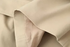 Gedetailleerde macro-opname van de gladde stoftextuur en voering van een kaki trenchcoat