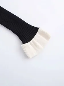 Detail of V-neck knit sweater featuring elegant black and white contrast ribbed cuffs.