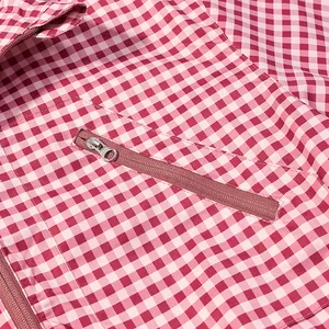 Detailed view of pink gingham windproof jacket showing a functional zipper pocket