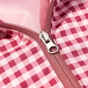 Detailed close-up showing a smooth metal zipper on a pink and white gingham windbreaker jacket.