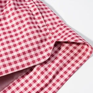 Detailed close-up view of pink and white gingham jacket pocket and curved hemline