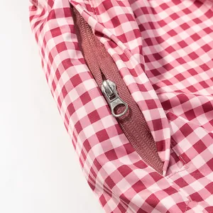 Close-up detail of the metal zipper and pink gingham fabric on a spring windbreaker