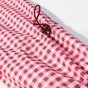 Close-up detail of red and white gingham jacket featuring a brown drawstring toggle stopper