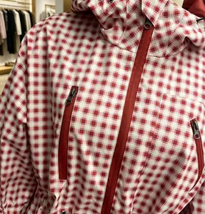 Close-up detail of red and white checkered hooded windbreaker jacket with zip pockets