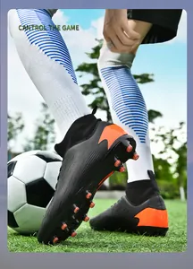 Primer plano de botas de fútbol de caña alta negras y naranjas para hombre en césped.