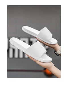 Vue détaillée de claquettes blanches minimalistes à semelle souple tenues à la main